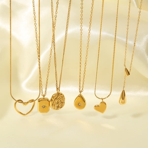 Minimalist gold plated necklaces featuring heart and geometric pendants on silk background
