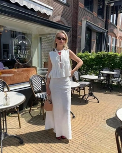 Chic white linen two-piece set featuring pleated sleeveless tie-front top and maxi skirt