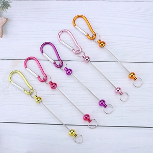 DIY metal D-ring carabiner keychains in assorted vibrant colors on white wooden desk