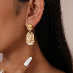 Gros plan de boucles d'oreilles dorées géométriques avec motif spirale sur mannequin