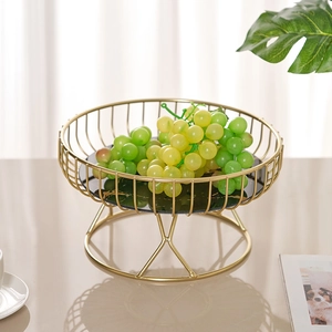 Golden iron fruit basket with black marble base on a sleek reflective tabletop surface
