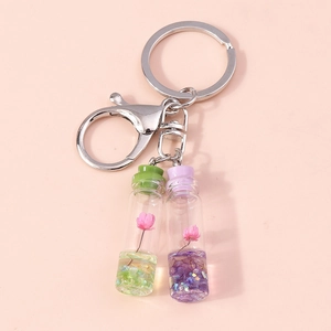Wish bottle keychain with pink dried flowers and colorful glitter liquid on pink background