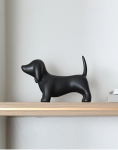 Detailed side view of a minimalist matte black ceramic dachshund figurine on a shelf