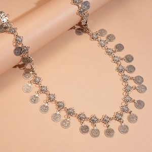 Macro detail of vintage silver flower waist chain with embossed coin pendants on props
