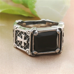 Macro detail of vintage punk cross ring with black stone and engraved silver steel pattern