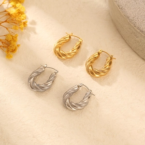 Detailed close-up of gold and silver U-shaped hoop earrings with braided texture detail