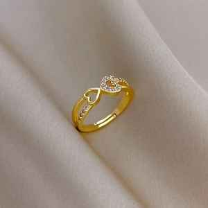 Detailed view of a gold heart-shaped ring with micro-inlaid stones on champagne silk fabric