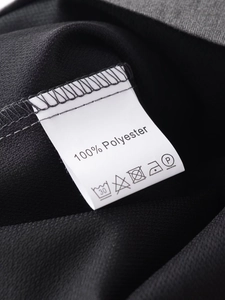 Detail des Pflegeetiketts mit 100% Polyester-Zusammensetzung auf schwarzen Faltenhosen