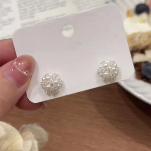 Detail of elegant pearl cluster stud earrings on a display card with silver base