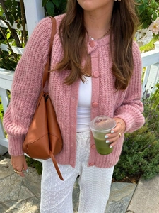 Detailed view of pink knitted button-down cardigan with round neck and long sleeves