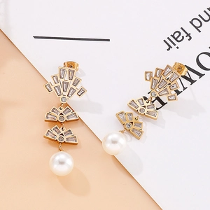 Detailed macro view of gold tassel earrings with fan-shaped crystal inlay and round white pearl