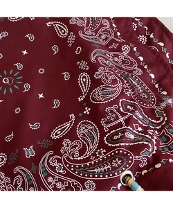 Macro detail of wine red paisley print fabric with metal eyelet and woven drawstring cord