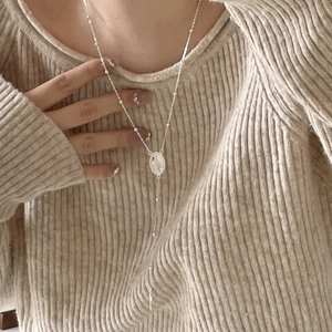 Close-up of a 925 sterling silver Maria medal and cross pendant on a beaded Y-necklace
