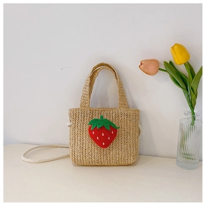 Detail of straw woven bag featuring a red strawberry pattern and woven crossbody strap