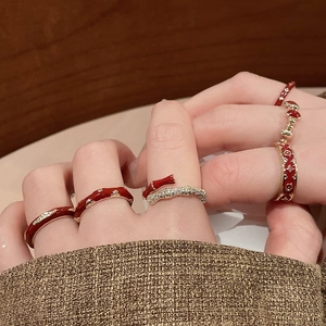 Detail showing stacked 14k gold plated rings with red enamel and monogram pattern