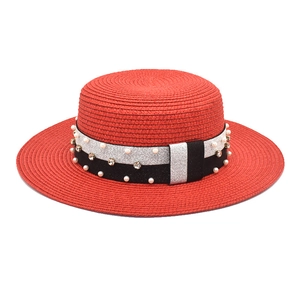 Detail of red boater straw hat featuring a sparkling band with pearls and rhinestones