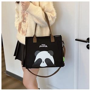 Detail of black canvas tote bag featuring a cute panda print and dual handle straps