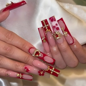 Long red French press-on nails with golden rose, cross, and gemstone 3D decorations