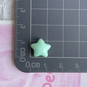 Detailed view of a 1.2cm mint green resin star charm on a measuring scale mat