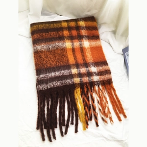 Close-up of soft plaid winter scarf with tassels in warm brown and orange tones
