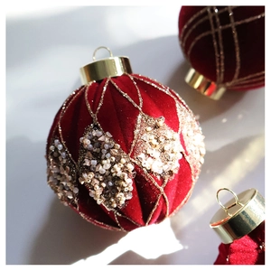 Macro detail of red velvet Christmas ball with gold glitter grid and beadwork