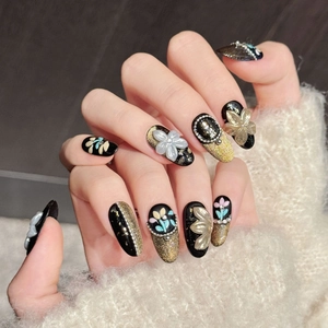 Handmade black and gold press-on nails with 3D white flowers and pearl accents
