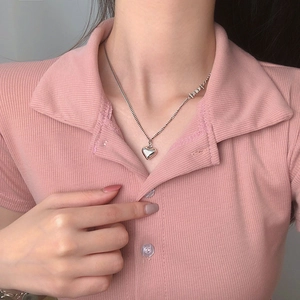 Close-up of a silver heart pendant necklace with fine chain worn by a model