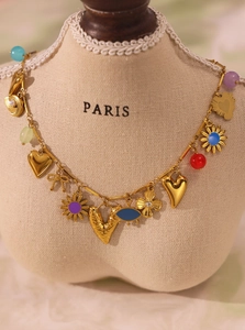 Close-up of colorful heart and floral charms on a gold-plated necklace for summer fashion