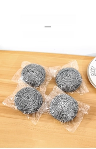 Set of four steel wool cleaning scrubbers in individual packaging on a wooden table