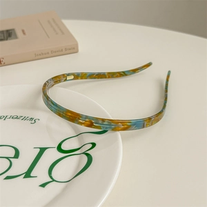 Detail shot of a slim acetate headband with marble texture on a ceramic display