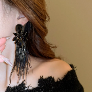 Close-up of black gemstone feather drop earrings with long tassels on female model
