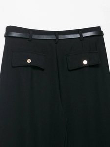 Dettaglio di pantaloni eleganti neri con cintura in pelle e bottoni dorati