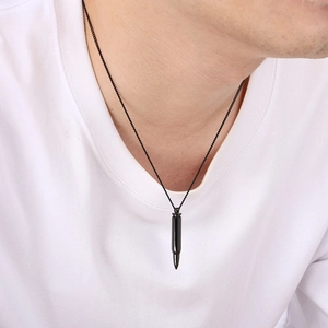 Close-up of a polished black bullet pendant necklace worn on a white t-shirt for men