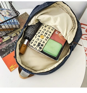 Detailed top view showing internal storage space and lining of denim backpack