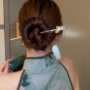 Détail de l'épingle à cheveux muguet avec perle et gland de feuille verte sur le chignon