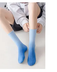 Close-up of blue gradient mid-calf crew socks with ribbed cuffs on model's feet