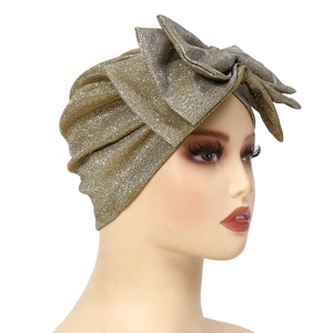 Close-up of golden glitter turban hat with a large hand-stitched decorative bow