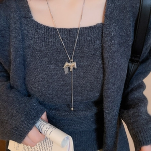 Detail of silver long sweater chain featuring a hollow horse pendant with delicate tassels