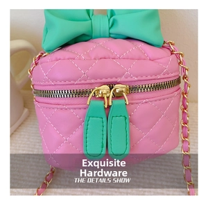 Detailed shot of pink quilted crossbody bag with green bow and gold chain hardware