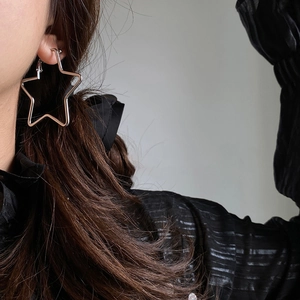 Minimalist silver star hoop earring worn by a model in a high-fashion side profile shot