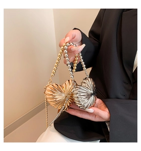Detail of a mini crossbody heart bag with metallic finish and beaded handle