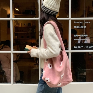 Detail of pink plush tote bag with white flower pattern in a cozy winter outdoor setting