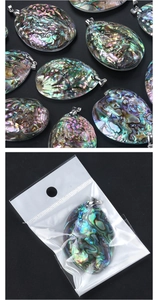 Detail view of large abalone shell pendants with metal bezel and poly bag packaging