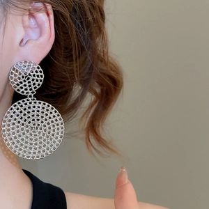 Detail shot of large silver hollow mesh circular earrings worn by a female model