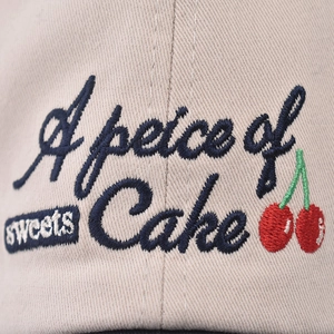 Beige washed cotton baseball cap featuring cherry embroidery and cake lettering