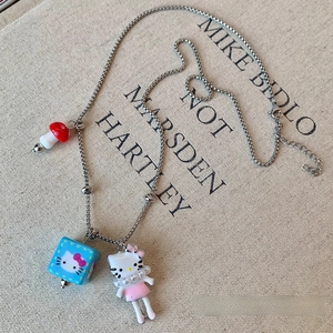Detail of silver chain necklace with Hello Kitty charms and mushroom pendant