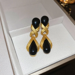 Vintage gold metal geometric earrings with black resin teardrop charms on jewelry box