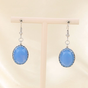 Detailed view of oval blue glass drop earrings hanging on a display stand