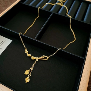 Detailaufnahme der goldenen Halskette mit Blattmotiven und Quasten auf schwarzem Samt
