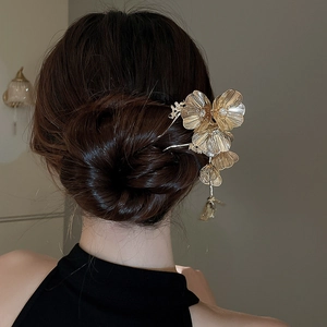 Macro detail of golden flower hair pin with sparkling zircons and a delicate tassel